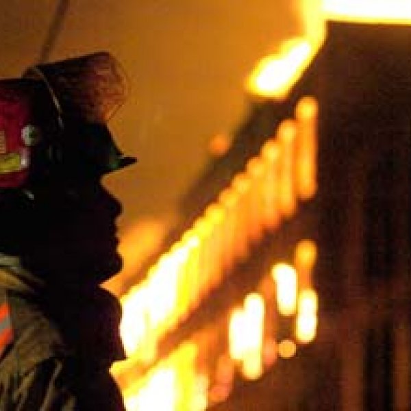 a firefighter looking at a burning building