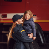 A female firefighter holding a smiling child